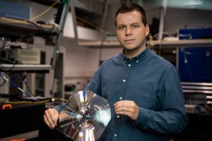 Dr Filip Sośnicki with a standard, spatial Fresnel lens. Its temporal analogue was used in the conducted research. Photo by M. Kaźmierczak/UW